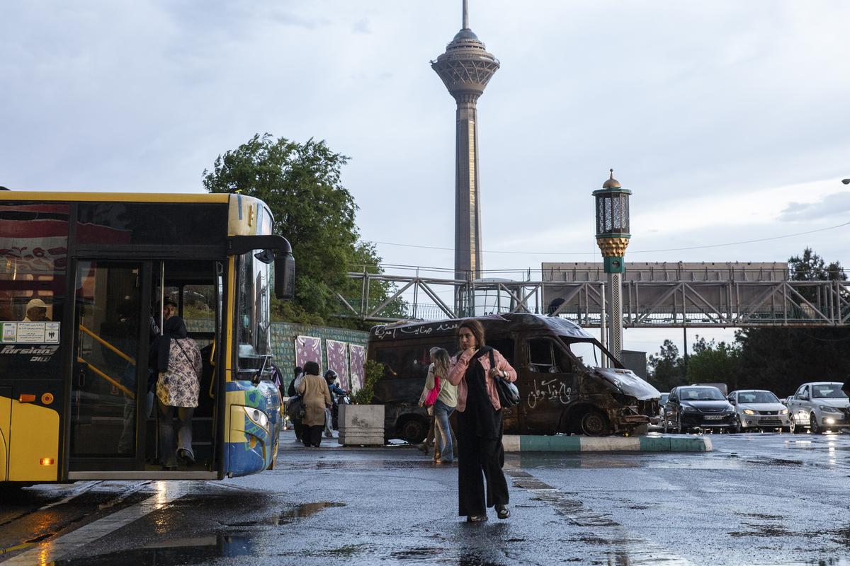 People board a bus at an intersection with an ambulance destroyed amid U.S.-Israeli strikes on display in Tehran, on Tuesday, April 28, 2026. Oil prices continued to climb on Tuesday, as peace talks between the United States and Iran appeared at an impasse, with negotiators deadlocked over proposals to reopen the Strait of Hormuz to tanker traffic and restrict Iran's nuclear program. (Arash Khamooshi/The New York Times)
