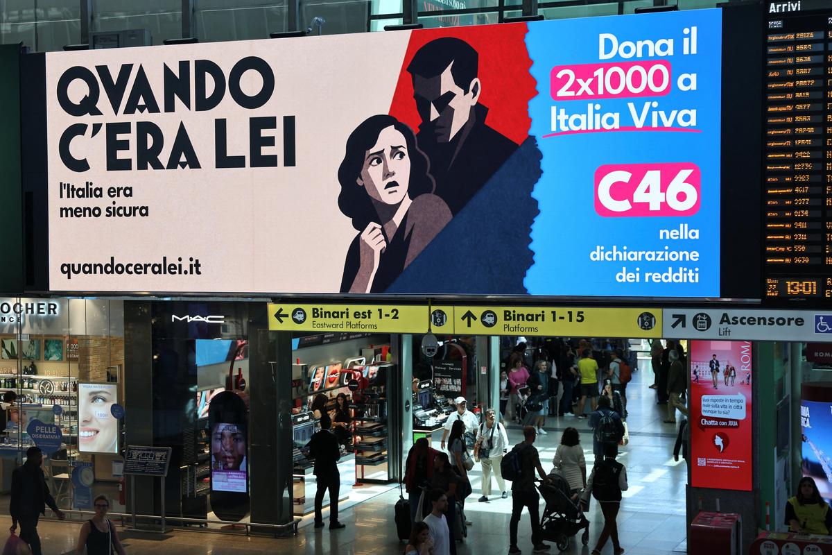 People walk past an advertisement, commissioned by Italia Viva at Roma Termini railway station, referring to Italian Prime Minister Giorgia Meloni, reading in English, "When she was around, Italy was less safe" and featuring imagery and typography reminiscent of Italian fascist-era propaganda from the 1930s, in Rome, Italy, May 22, 2026. REUTERS/Yara Nardi