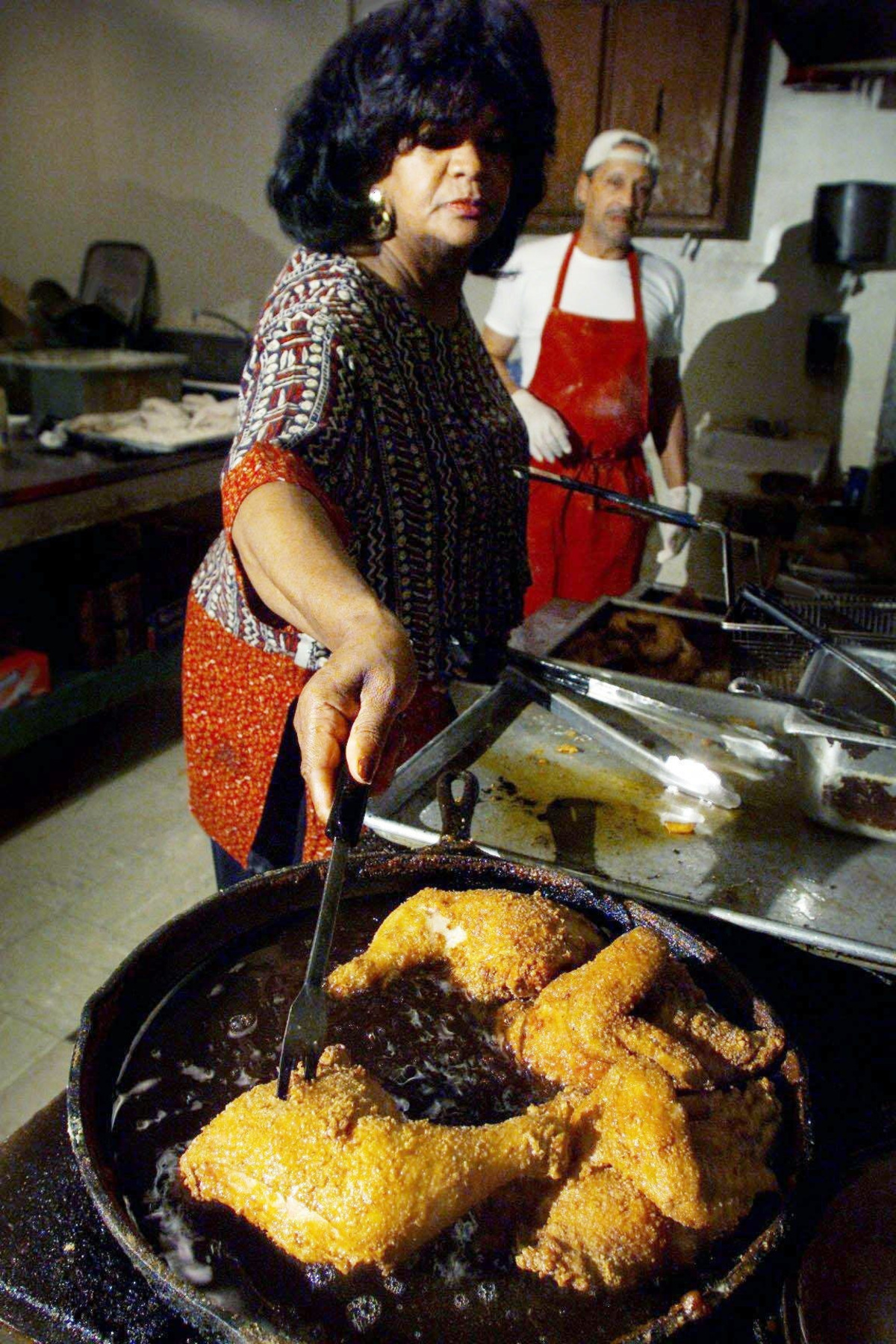 Andre Prince, left, owner of Prince's Hot Chicken Shack in Nashville, fries up a batch of chicken in the kitchen alongside cook Larry Alexander on Oct. 18, 2002.