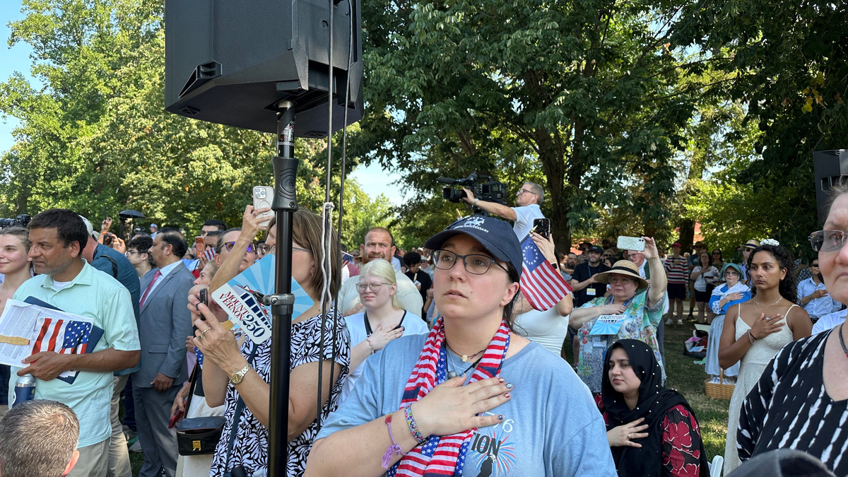 Woman at naturalization ceremony places her right hand over her heart during the Pledge of Allegiance.