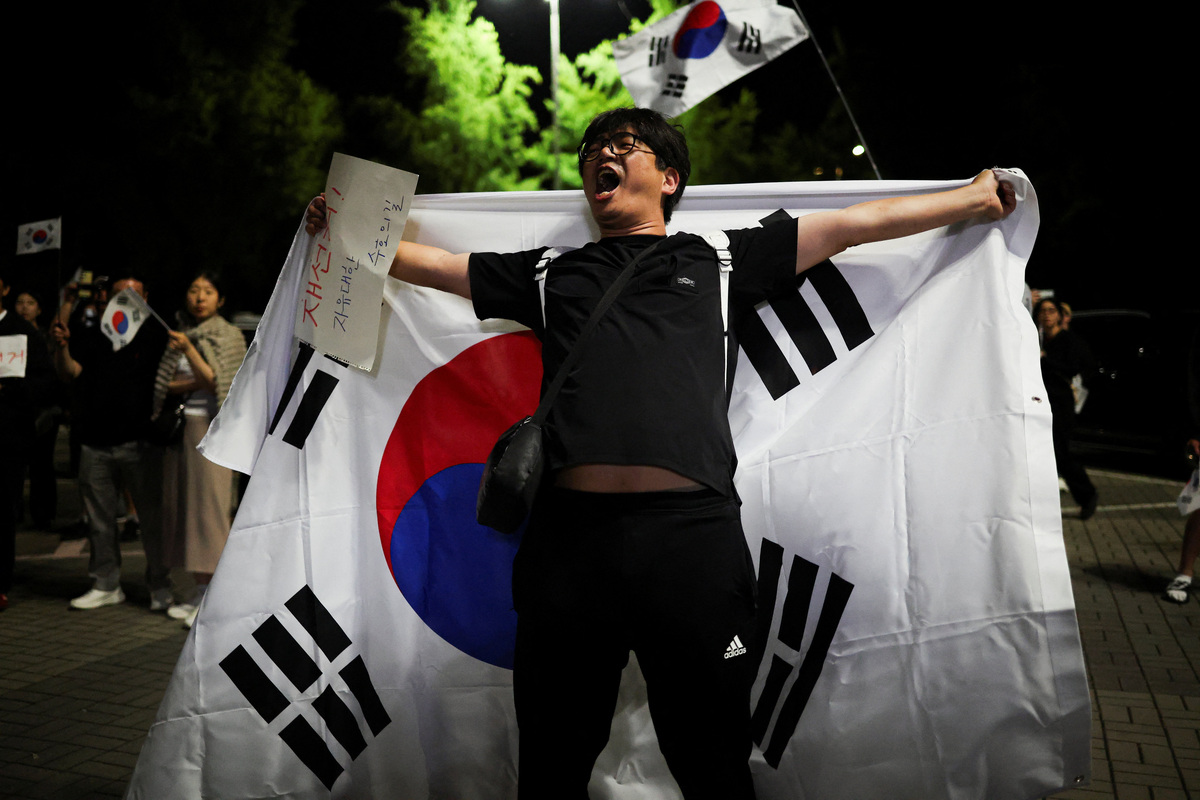 A demonstrator holds a large South Korean flag and a sign reading "Rerun election" while chanting the same slogan, as people surround a vote-counting centre to protest a controversy over a shortage of ballot papers that disrupted voting in the local election and to call for a rerun of the election, in Seoul, South Korea, June 6, 2026. REUTERS/Kim Hong-Ji