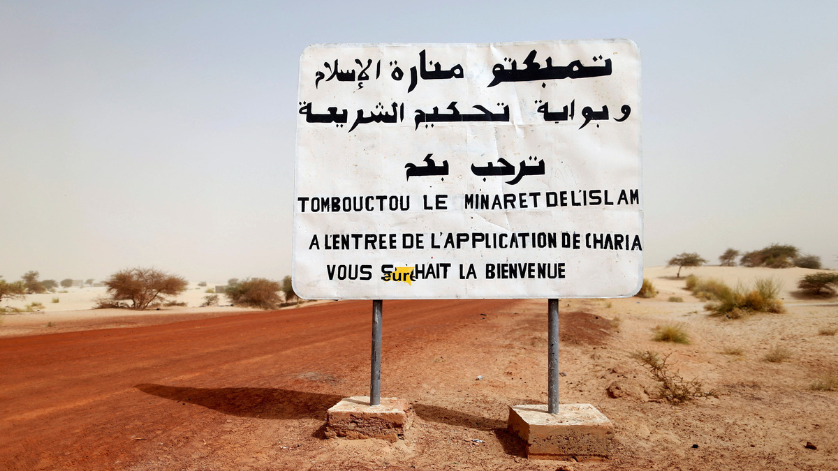 FILE PHOTO: A road sign written by Islamist rebels is seen at the entrance into Timbuktu January 31, 2013. The sign reads, "Timbuktu, the minaret of Islam and the entrance to the application of the Sharia law welcomes you."  REUTERS/Benoit Tessier/File Photo