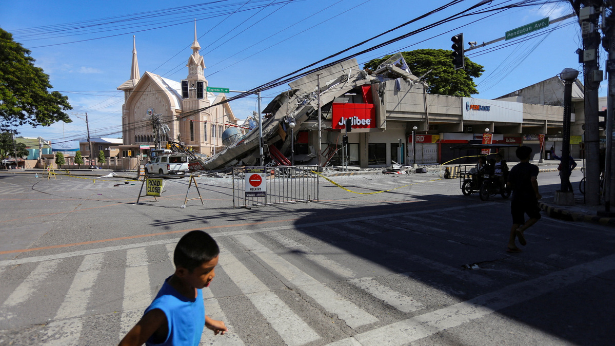 People walk near a collapsed building following the magnitude 7.8 quake in General Santos, southern Philippines, June 8, 2026. REUTERS/Manman Dejeto