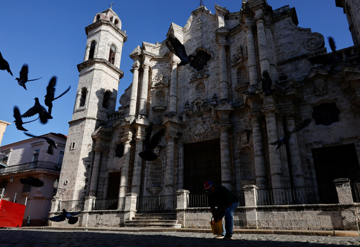 Iraldo Garcia, an employee of the Office of the Historian of Havana, feeds pidgeons at Cathedral Square, one of the most popular tourist spots in Old Havana, as U.S. sanctions have led most major tourism and travel companies to leave the island or drastically scale back their operations, in Havana, Cuba June 8, 2026. REUTERS/Norlys Perez