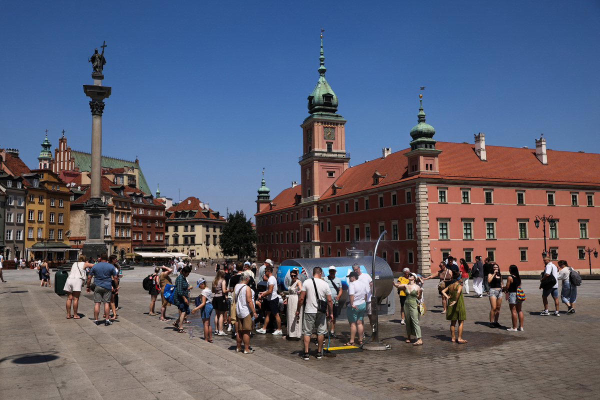People gather at Castle Square under water curtains and near a tanker providing free drinking water during a heatwave, in Warsaw, Poland, June 28, 2026. REUTERS/Kuba Stezycki