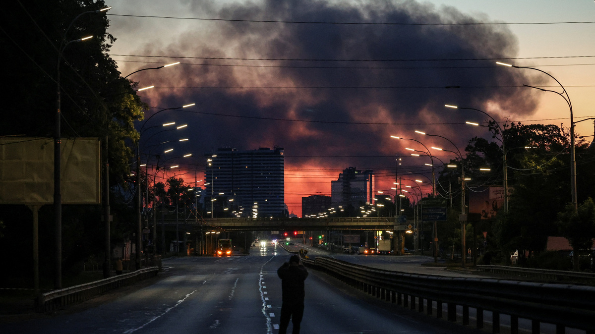 A man takes a picture of a street as smoke rises in the background after an overnight Russian missile and drone strike, amid Russia's attack on Ukraine, in Kyiv, Ukraine June 2, 2026. REUTERS/Alina Smutko