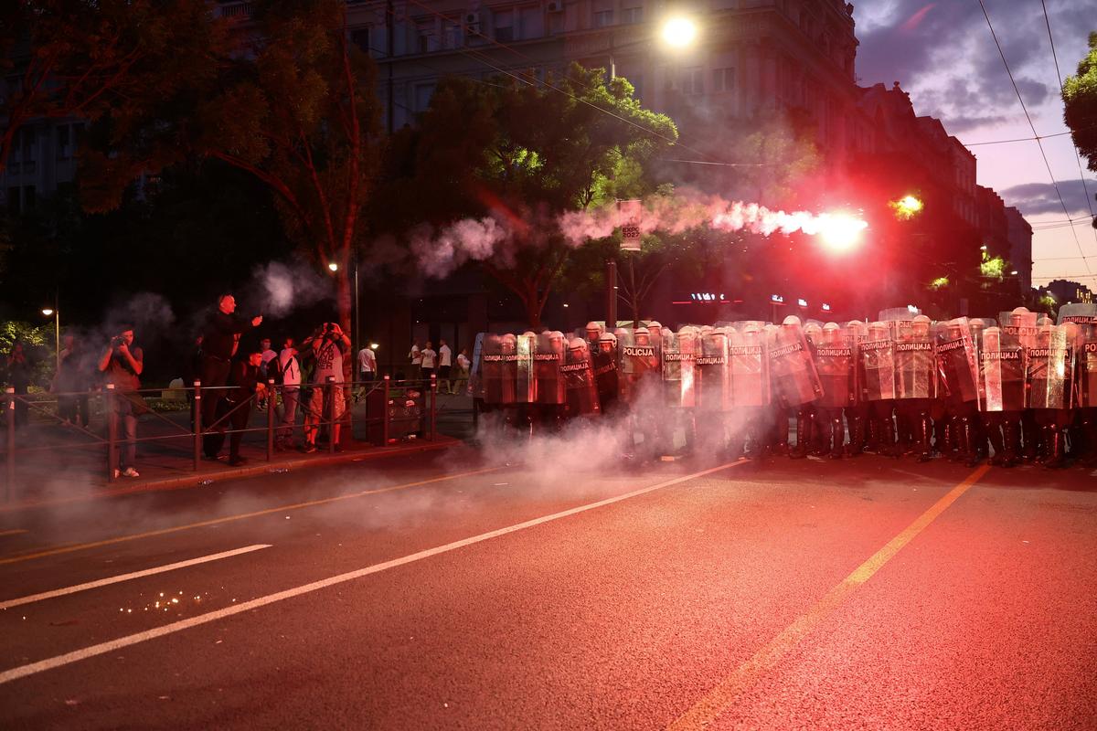 Riot police stand guard as a smoke flare moves through the air after being thrown, during a student-led protest demanding snap parliamentary elections, as Serbia's anti-corruption movement enters a new phase, following the Novi Sad railway station canopy collapse that killed 16 people in 2024, in Belgrade, Serbia, May 23, 2026. REUTERS/Zorana Jevtic