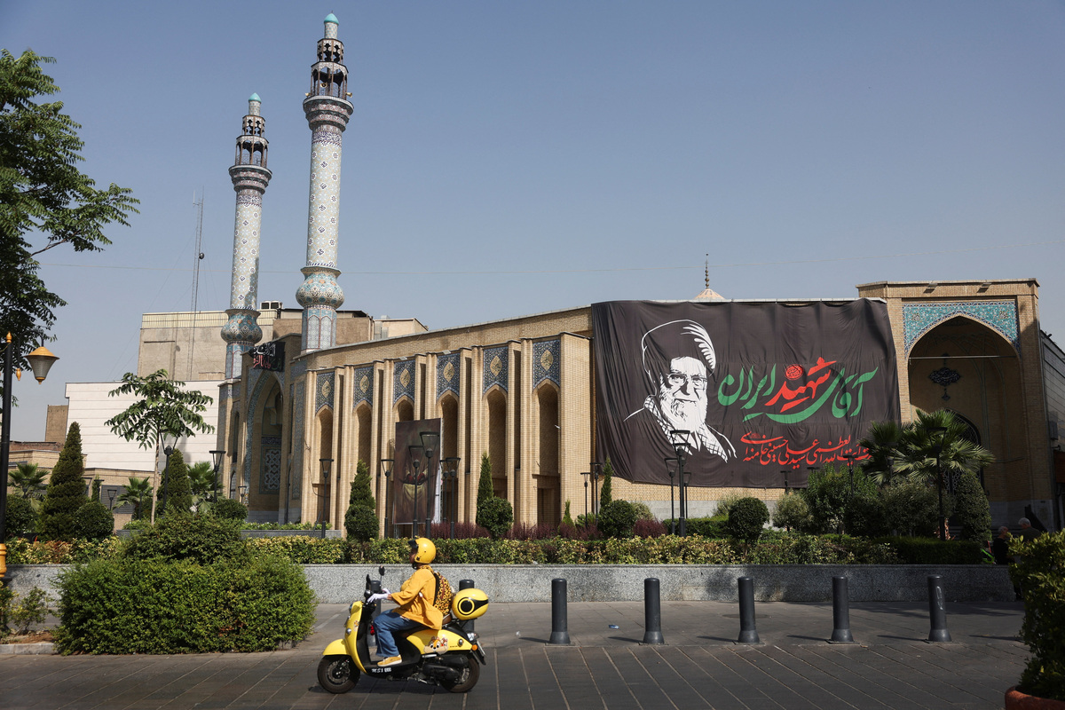 An Iranian woman rides a motorcycle next to a banner with a picture of the late Supreme Leader of Iran, Ayatollah Ali Khamenei, on a street in Tehran, Iran, July 12, 2026. Majid Asgaripour/WANA (West Asia News Agency) via REUTERS