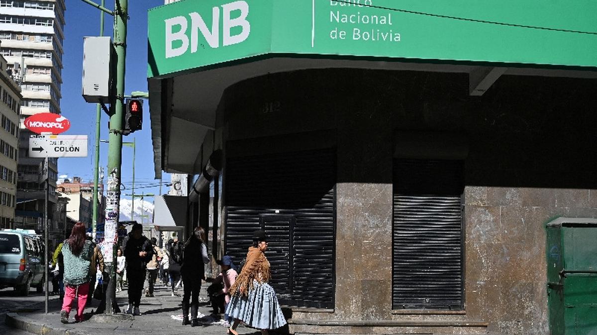 People walk past a closed branch of the National Bank of Bolivia in La Paz as several of the country’s banks temporarily closed branches due to ongoing unrest driven by anti-government demonstrations on Tuesday.