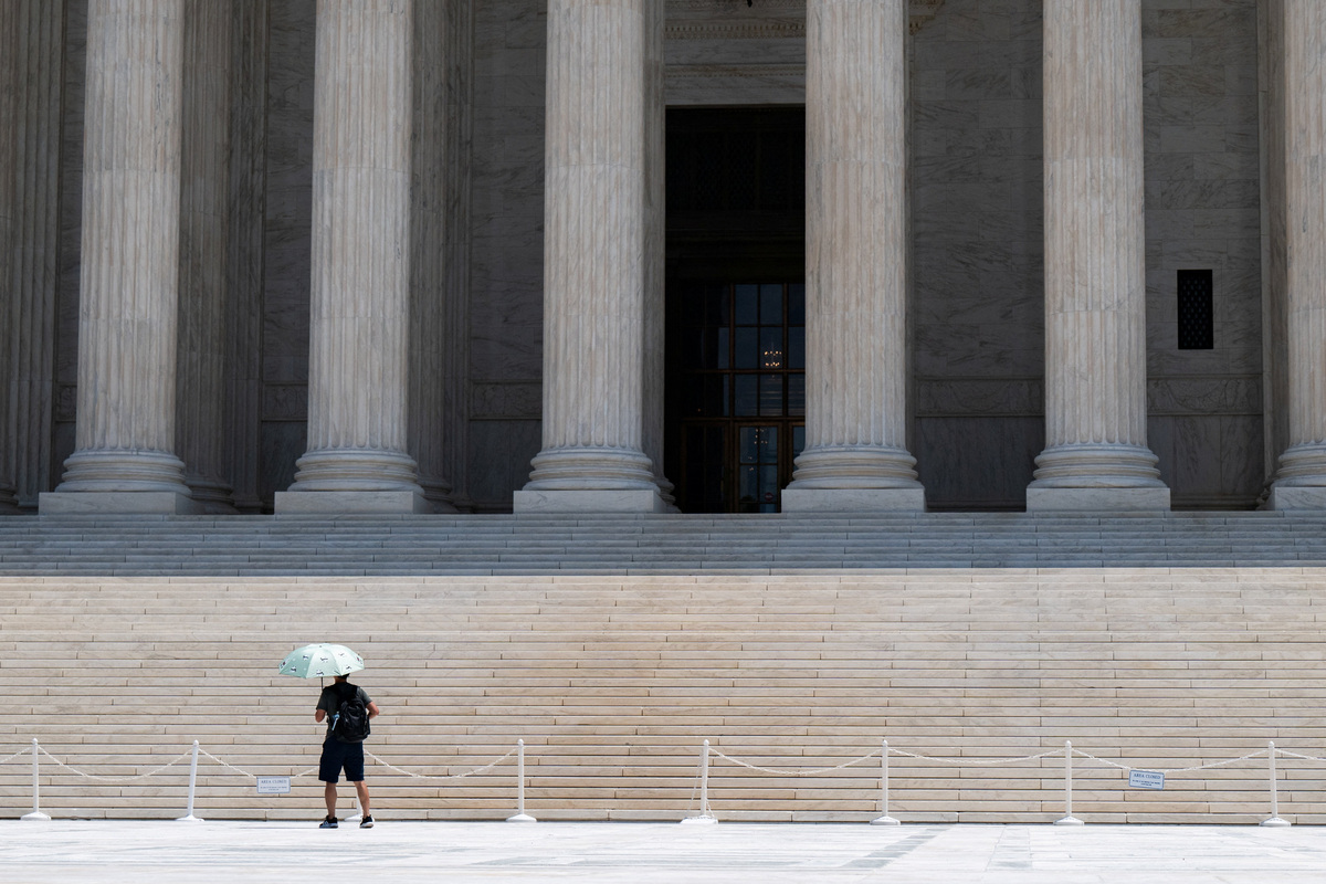 A person uses an umbrella to block the sun at the Supreme Court amid a heatwave in Washington, D.C., U.S., July 1, 2026. REUTERS/Annabelle Gordon