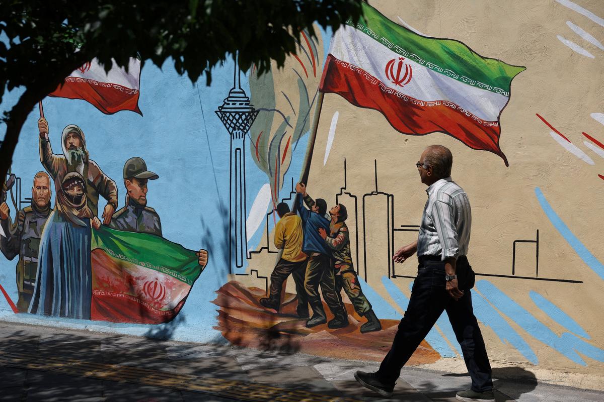 An Iranian man walks next to a mural on a street in Tehran, Iran, May 11, 2026. Majid Asgaripour/WANA (West Asia News Agency) via REUTERS