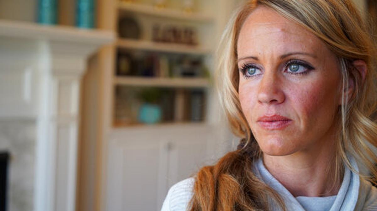 In this March 27, 2019, photo, Kacey Ruegsegger Johnson poses for a portrait at her home in Cary, N.C. Ruegsegger Johnson, now a mother of four, survived a shotgun blast during the 1999 shootings at Colorado’s Columbine High School that left 12 students, one teacher, and both gunmen dead. The emotional toll of the shooting, joined by fears about their own kids’ safety, spikes each time yet another shooter enters another school.