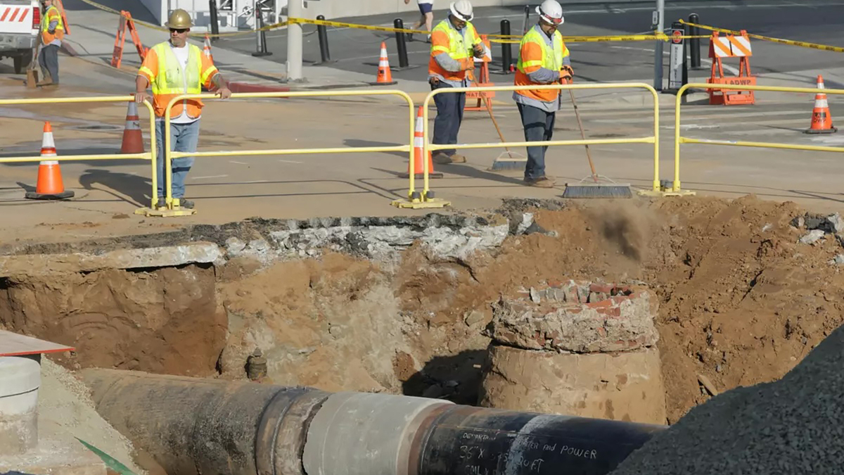 Workers sweep the street over the side to a water main rupture on Sunset Boulevard in West Hollywood on Saturday, July 18, 2026. The rupture of a 3-foot-wide trunk line Thursday morning sent 17 million gallons of water into a West Hollywood neighborhood. (Myung J. Chun/Los Angeles Times/TNS)