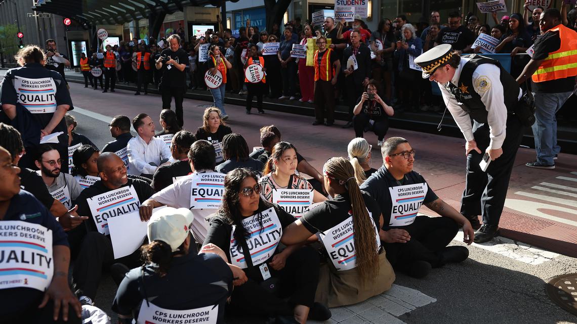 Chicago Public Schools lunchroom workers sit in the street in front of the Chicago Board of Education on Madison Street before being detained by police in an act of civil disobedience, Thursday, April 23, 2026. The group was protesting after 11 month of contract negotiations. (Chris Sweda/Chicago Tribune/TNS)