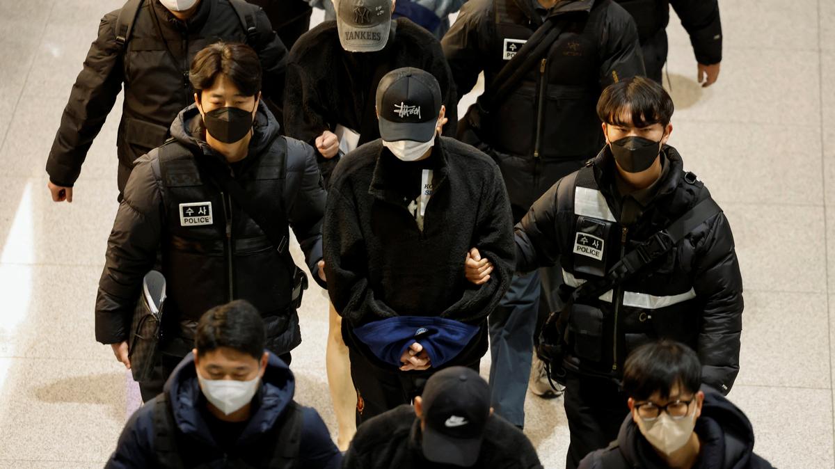 FILE PHOTO: Police officers escort South Koreans allegedly involved in scam operations in Cambodia after being forcibly repatriated from Cambodia, at Incheon International Airport in Incheon, South Korea January 23, 2026. REUTERS/Kim Soo-hyeon/File Photo