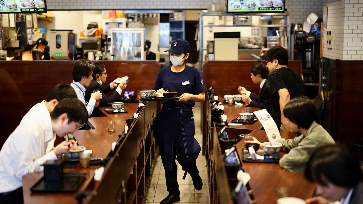 A staff member serves 'gyudon' beef bowl to customers inside Yoshinoya restaurant in Tokyo, Japan May 19, 2025.  REUTERS/Issei Kato