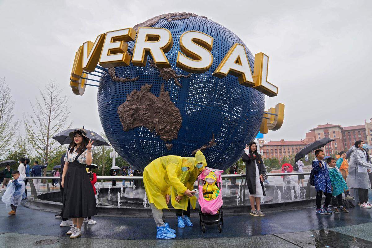 A family wearing raincoats and face masks to help protect themselves from the coronavirus pose for a selfie with an icon near the entrance to the Universal Studios Beijing. (AP Photo/Andy Wong)