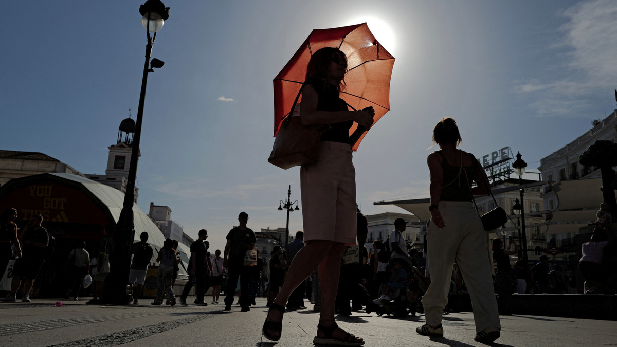FILE PHOTO: A woman with an umbrella walks at Plaza Puerta del Sol during a spring heatwave in Madrid, Spain, May 27, 2026. REUTERS/Kacper Pempel/File Photo