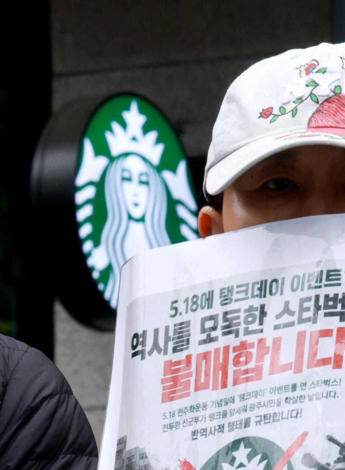 An activist holds a sign during a protest against Starbucks' "Tank Day" campaign, which was launched on the same day as the anniversary of the May 18 Gwangju uprising, when the then military government sent in troops and tanks to suppress mass rallies for democracy, in Gwangju, South Korea, May 21, 2026.   Yonhap via REUTERS   THIS IMAGE HAS BEEN SUPPLIED BY A THIRD PARTY. NO RESALES. NO ARCHIVES. SOUTH KOREA OUT. NO COMMERCIAL OR EDITORIAL SALES IN SOUTH KOREA.