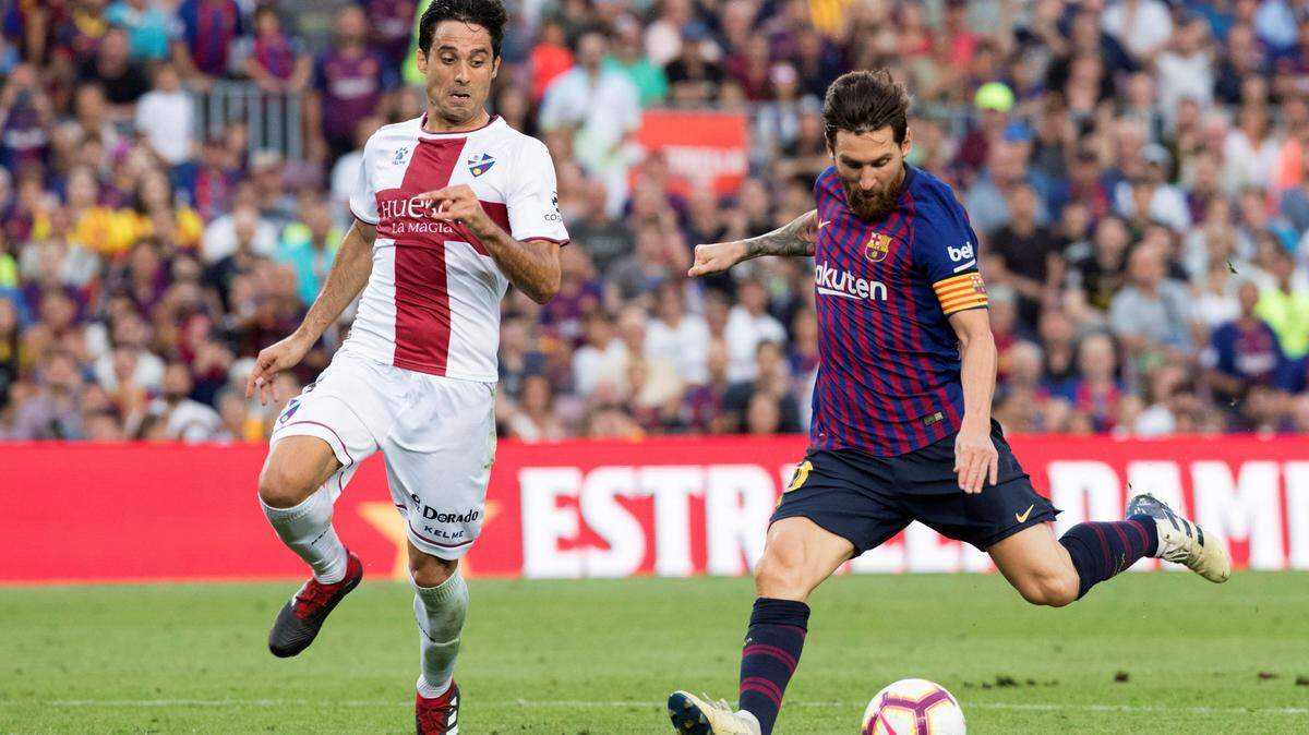 El delantero del Barcelona Lionel Messi (der.) patea el balón ante la marca de Xabier Etxeita, del Huesca, en el partido efectuado el  2 de septiembre de 2018.