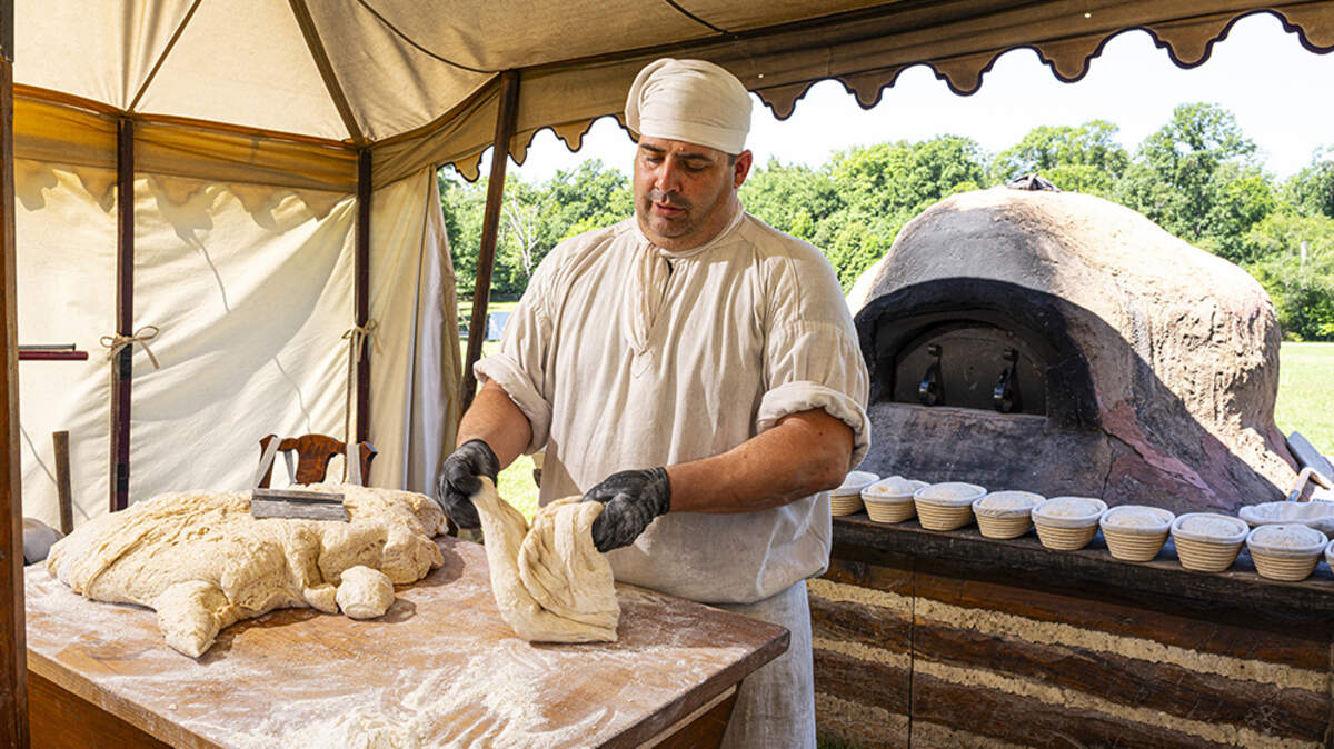 Justin Cherry, the baker-in-residence at Mount Vernon, prepares loaves of bread in his tent on the 12-acre field in front of George WashingtonÕs mansion in Mount Vernon, Va., June 13, 2026. CherryÕs breads are in demand this semiquincentennial, as is his knowledge of historical baking methods. (Scott Suchman/The New York Times)