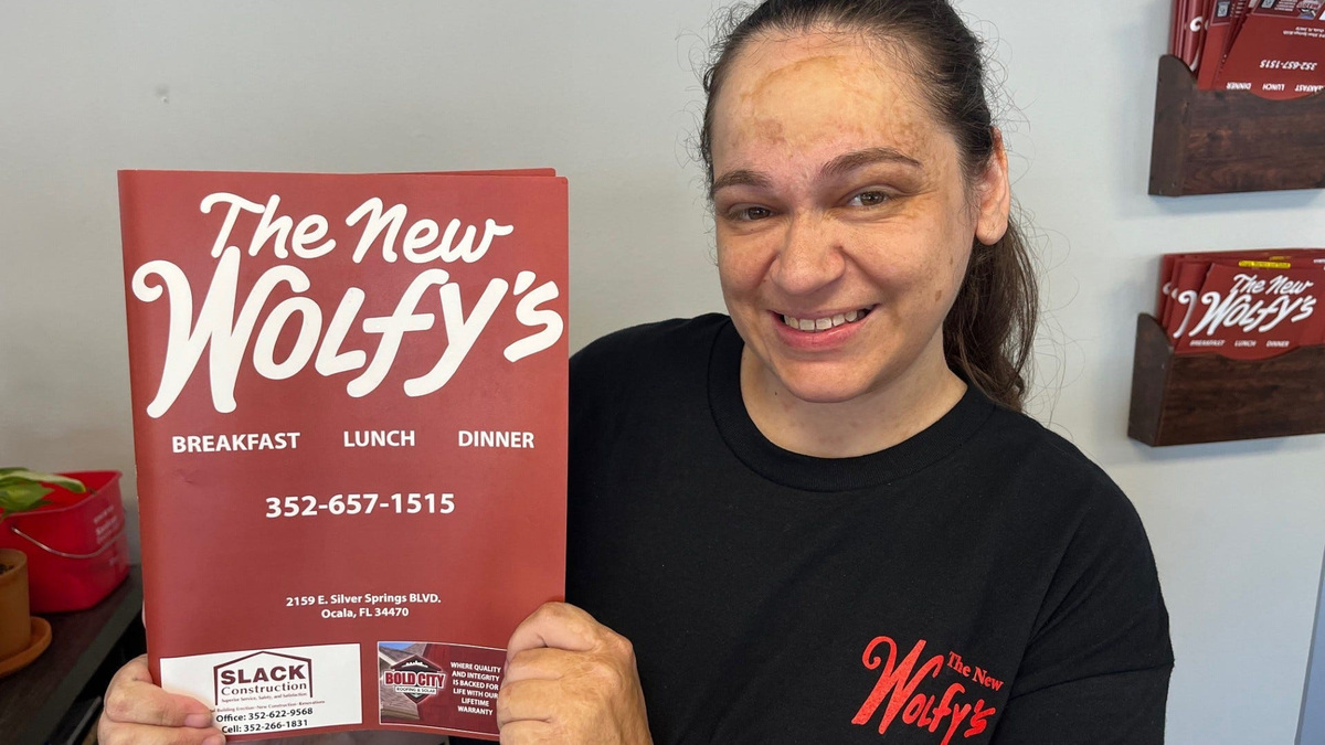 Amy Newvine, hostess, displays a menu for The New Wolfy’s restaurant on June 29, 2026.