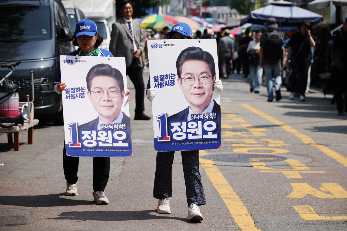 Supporters of Chong Won-o, Seoul mayoral candidate of the ruling Democratic Party, walk with signs before his campaign rally for upcoming June 3 local election, at a traditional market in Seoul, South Korea, June 2, 2026.    REUTERS/Kim Hong-Ji