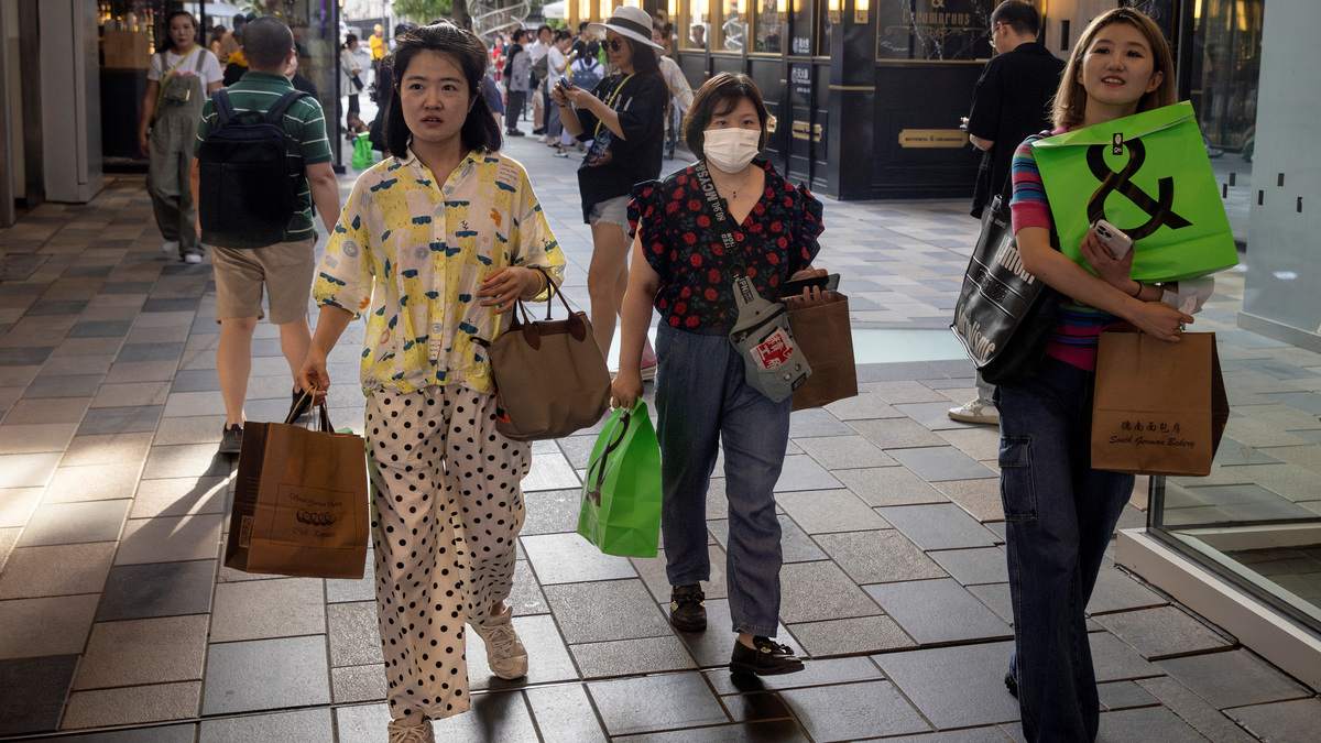 People carry shopping bags in a shopping district in Beijing, China, July 14, 2023. REUTERS/Thomas Peter