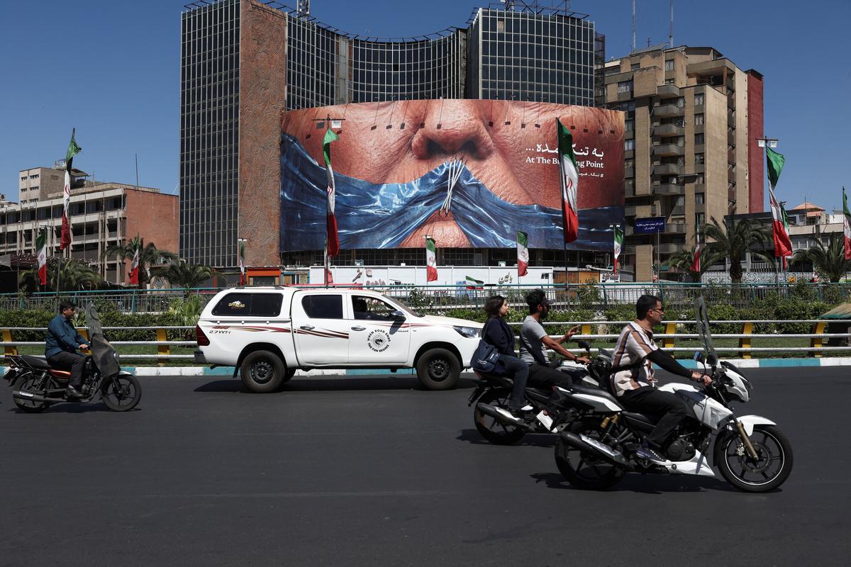 People ride past an anti-U.S. billboard depicting U.S. President Donald Trump and the Strait of Hormuz, in Tehran, Iran, May 25, 2026. Majid Asgaripour/WANA (West Asia News Agency) via REUTERS