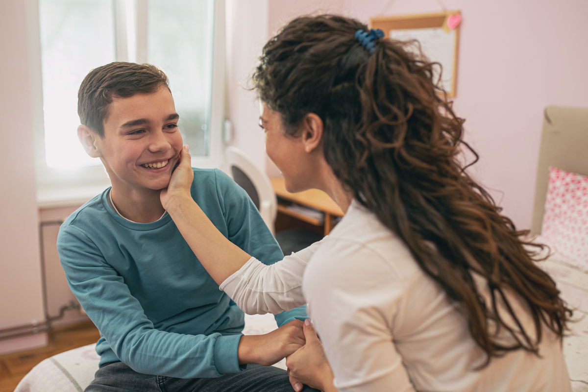  Stock photo: A happy mother touching and cuddling her teenage son on the face in his bedroom. 
