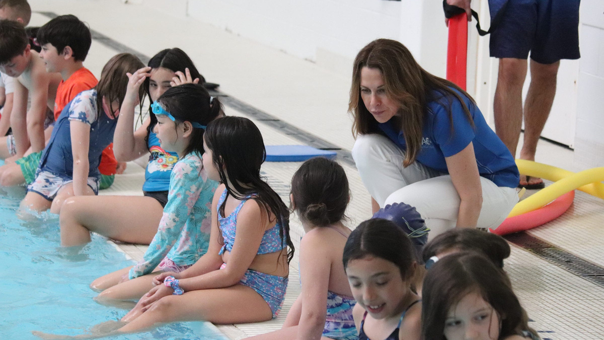 ZAC Foundation co-founder Karen Cohn chats with campers on a pool deck. The ZAC Foundation funds free water safety and swim camps for thousands of children every year.