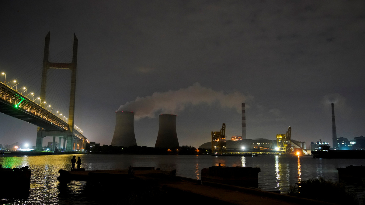 FILE PHOTO: People stand on a bank of the Huangpu river near a coal-fired power plant in Shanghai, China, October 14, 2021. REUTERS/Aly Song
