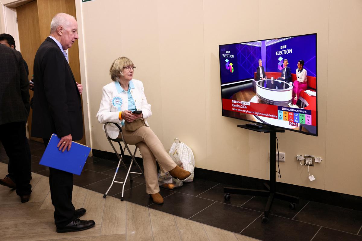 A woman wears a Reform UK party rosette while watching a news broadcast, following the results of the local elections, in the London Borough of Havering, Britain, May 8, 2026. REUTERS/Jack Taylor