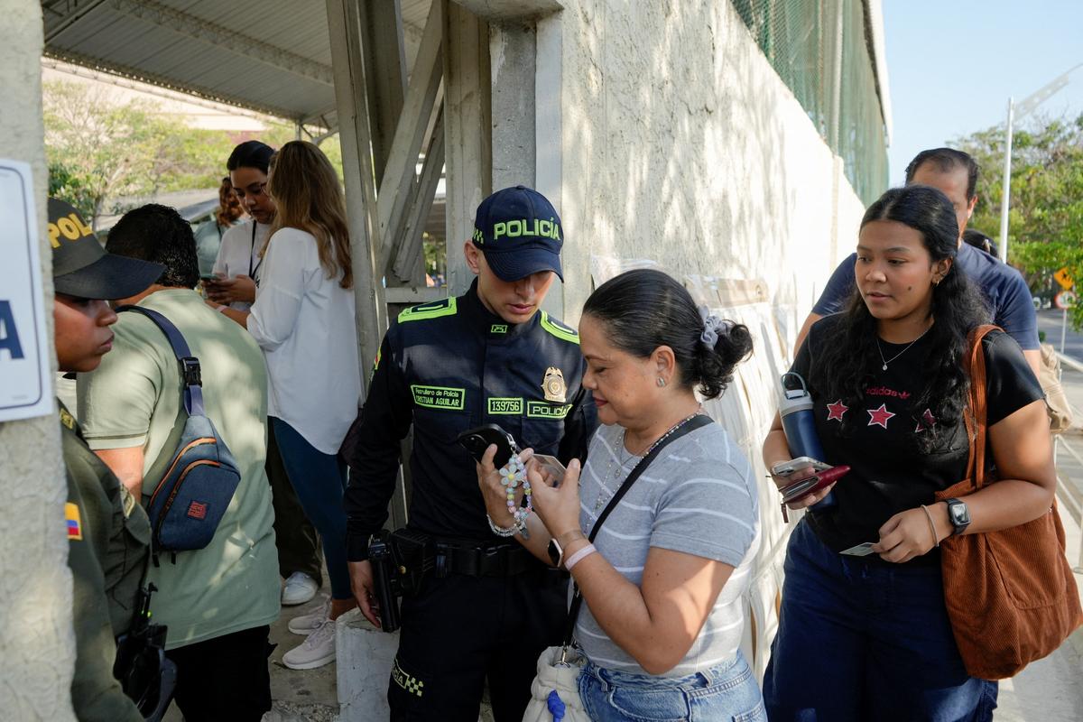 A police officer checks the indentity of a woman as she enters the polling station to cast a vote during the first round of the presidential election, in Barranquilla, Colombia May 31, 2026. REUTERS/Charlie Cordero