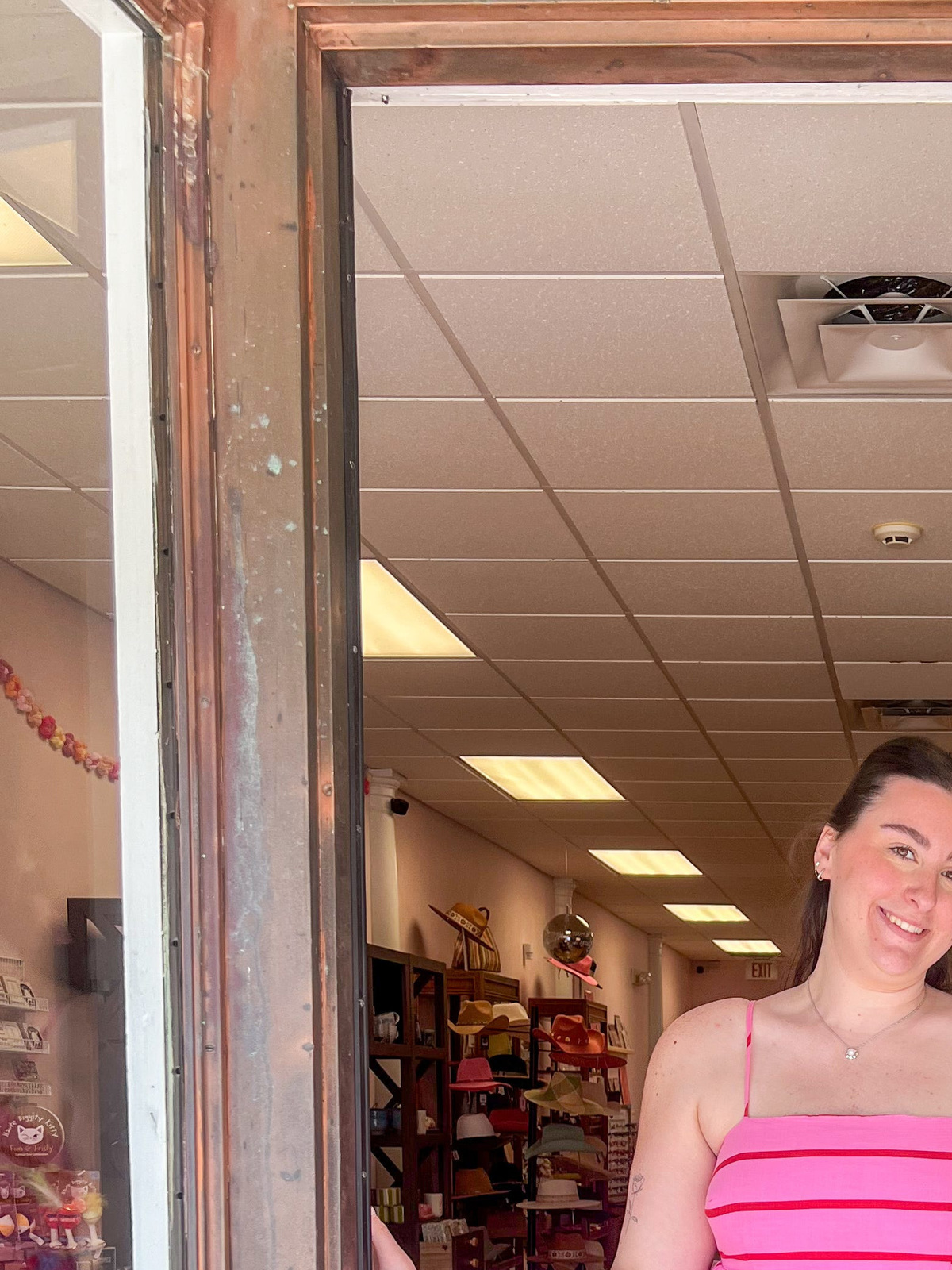 Lily Meglio stands at the front door of her boutique in Clinton, Conn.