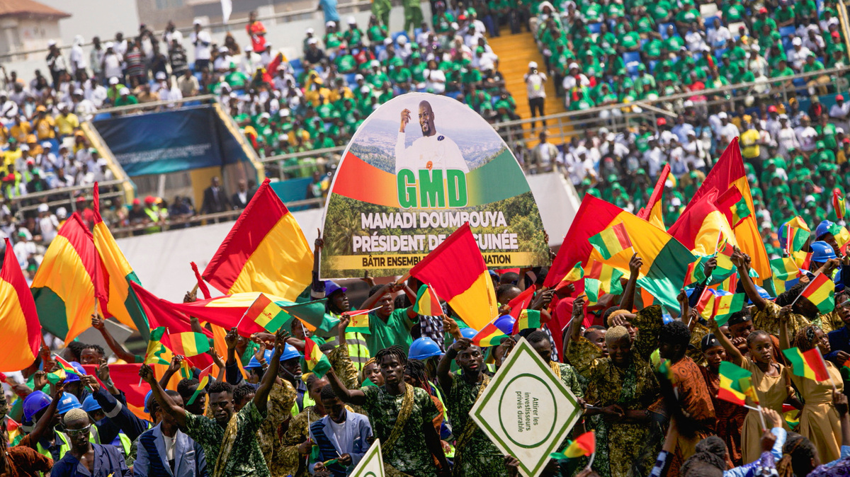 Supporters of Guinea's President-elect Mamady Doumbouya hold Guinean flags during his swearing-in ceremony in Conakry, Guinea, January 17, 2026. REUTERS/Souleymane Camara