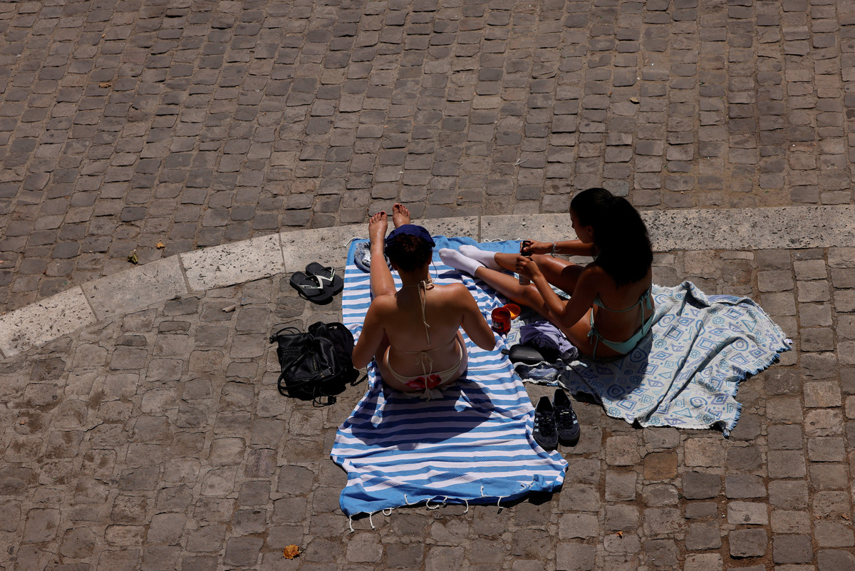 People sunbathe on the banks of the River Seine in Paris as temperatures rise during a heatwave affecting a large part of France, June 22, 2026. REUTERS/Alice Sacco