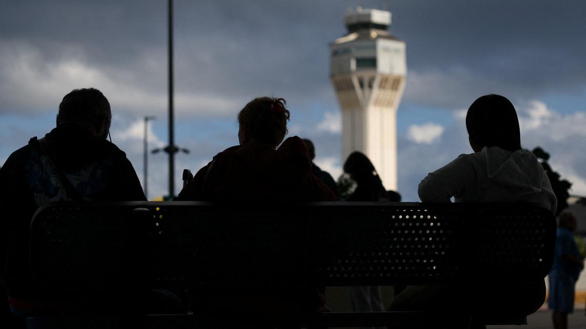 FILE PHOTO: Passengers sit on a bench, after flights were delayed and cancelled when the airspace was closed due to U.S. strikes on Venezuela overnight, at Luis Munoz Marin International Airport in Carolina, near San Juan, Puerto Rico January 3, 2026. REUTERS/Ricardo Arduengo/File Photo