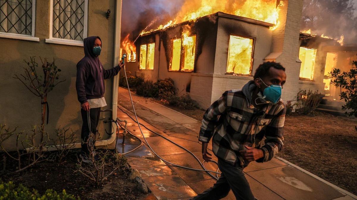 Samuel Girma runs to get another hose as he helps try to prevent a home from catching fire on LaPaz Rd. as the Eaton Fire continues to grow on Wednesday, Jan. 8, 2025, in Altadena, California. (Robert Gauthier/Los Angeles Times/TNS)