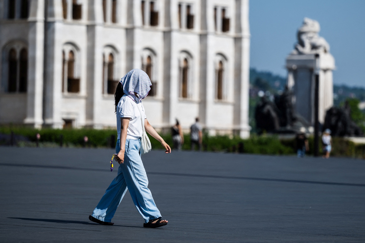 A woman shields herself from the sun with a towel over her head amid a heatwave in Budapest, Hungary, June 27, 2026. REUTERS/Marton Monus