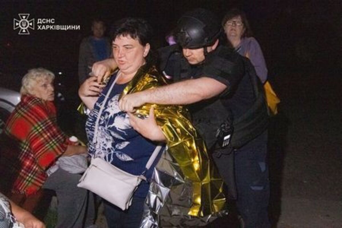 An emergency employee covers a woman with a thermal blanket at the site of a residential area damaged during overnight Russian missile and drone strikes, amid Russia's attack on Ukraine, in Kharkiv region, Ukraine June 9, 2026. Press service of the State Emergency Service of Ukraine in Kharkiv region/Handout via REUTERS