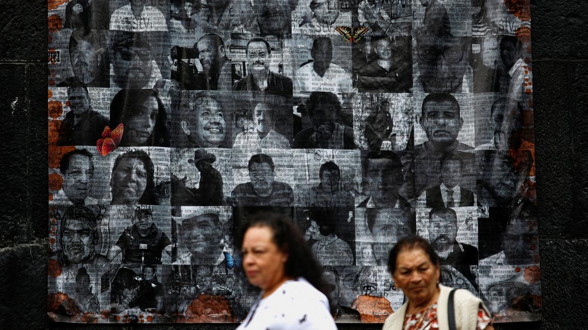 People walk by pictures of murdered journalists and activists displayed on an altar on the eve of the Day of the Dead in Mexico City, Mexico, October 31, 2022. REUTERS/Gustavo Graf/File Photo
