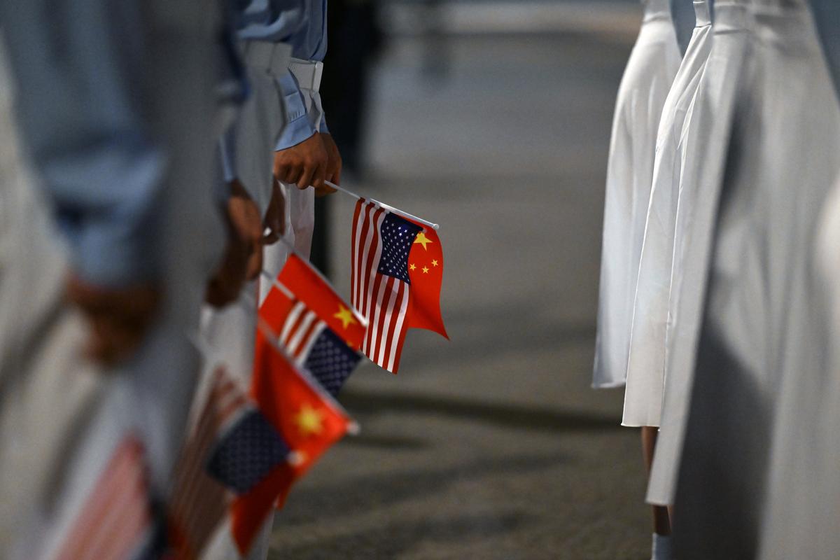 Holding Chinese and U.S. flags, members of the crowd assembled to welcome President Donald Trump await his arrival at Beijing Capital International Airport in Beijing, China, on Wednesday, May 13, 2026. Trump is in China for a two-day summit with China's leader, Xi Jinping. (Kenny Holston/The New York Times)