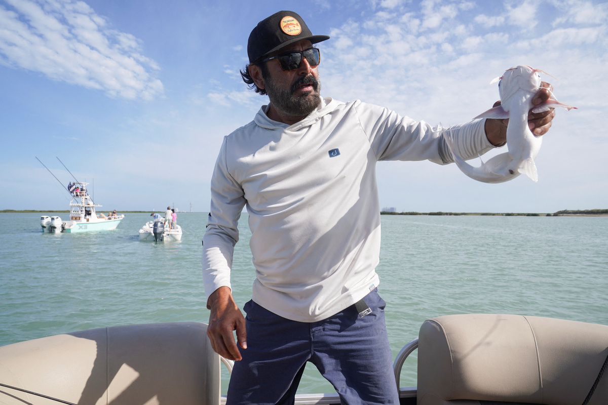 Eddie Reyes catches a fish that he will be releasing, as he waits with his family for the rocket launch ahead of SpaceX's initial public offering (IPO), in Port Isabel, Texas, U.S.  May 21, 2026.  REUTERS/Gabriel V. Cardenas