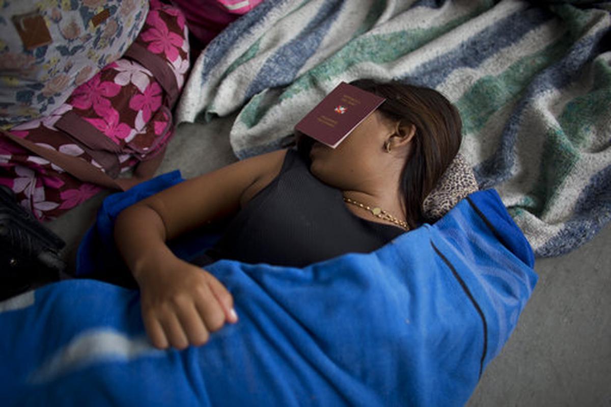 En esta foto del 7 de septiembre de 2018, una venezolana se cubre los ojos con un pasaporte “sanitario” peruano para dormir un poco cerca de la oficina de inmigración peruana en Tumbes, Perú.