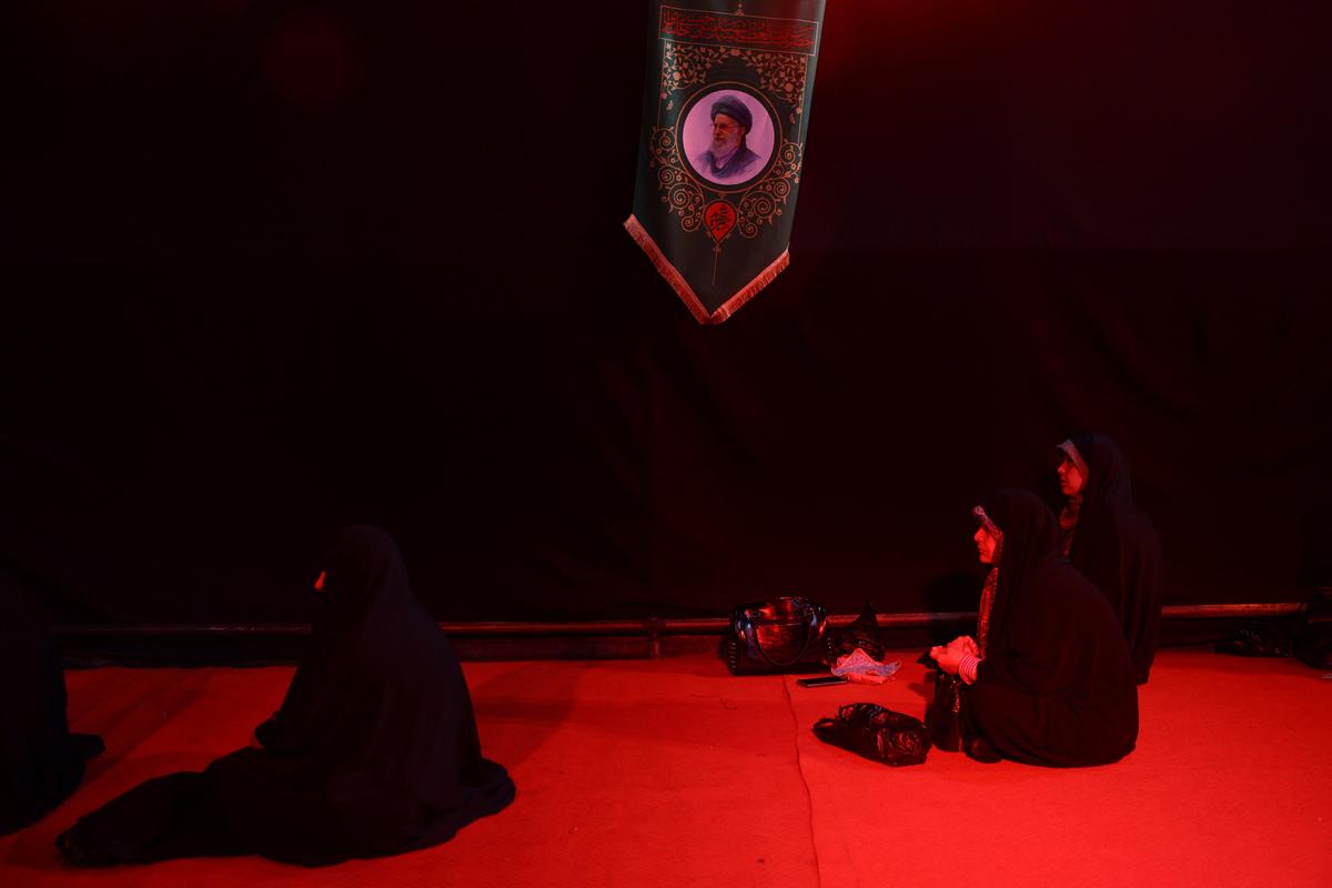 Iranian women pray next to a picture of the late Supreme Leader of Iran, Ayatollah Ali Khamenei, near his office in Tehran, Iran, May 6, 2026. Majid Asgaripour/WANA (West Asia News Agency) via REUTERS