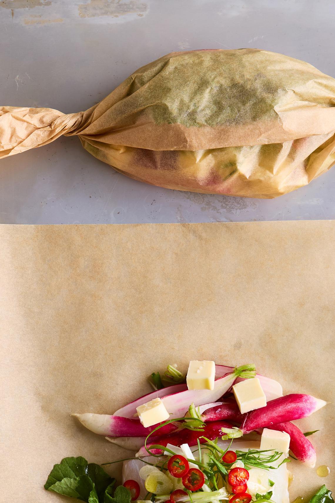 Parchment-steamed fish with buttered radishes. The completed packages look a bit like wrapped candies. Food styled by Brett Regot. (Ghazalle Badiozamani/The New York Times)