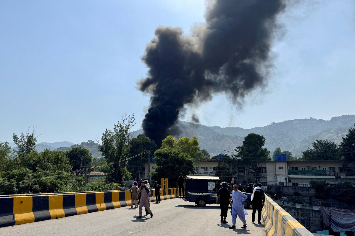 People and police gather nearby as smoke billows from the site where an Mi-17 helicopter of Pakistan Army Aviation crashed near Muzaffarabad, Pakistani Kashmir, June 10, 2026. Picture taken with a mobile phone. REUTERS/Tariq Maqbool