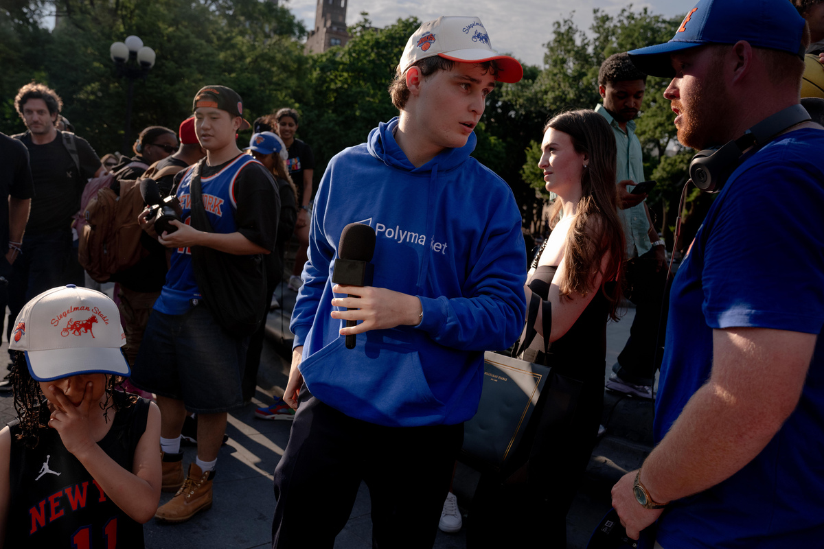 Jake Epstein, a content creator, talks to his videographer in Washington Square Park after hosting a Jalen Brunson look-alike contest in New York on June 17, 2026. Polymarket, one of the biggest prediction markets in the United States, bankrolled the contest; it was another reminder of the ubiquity of the industry, which was on display across New York City during the NBA finals. (Lexi Parra/The New York Times)