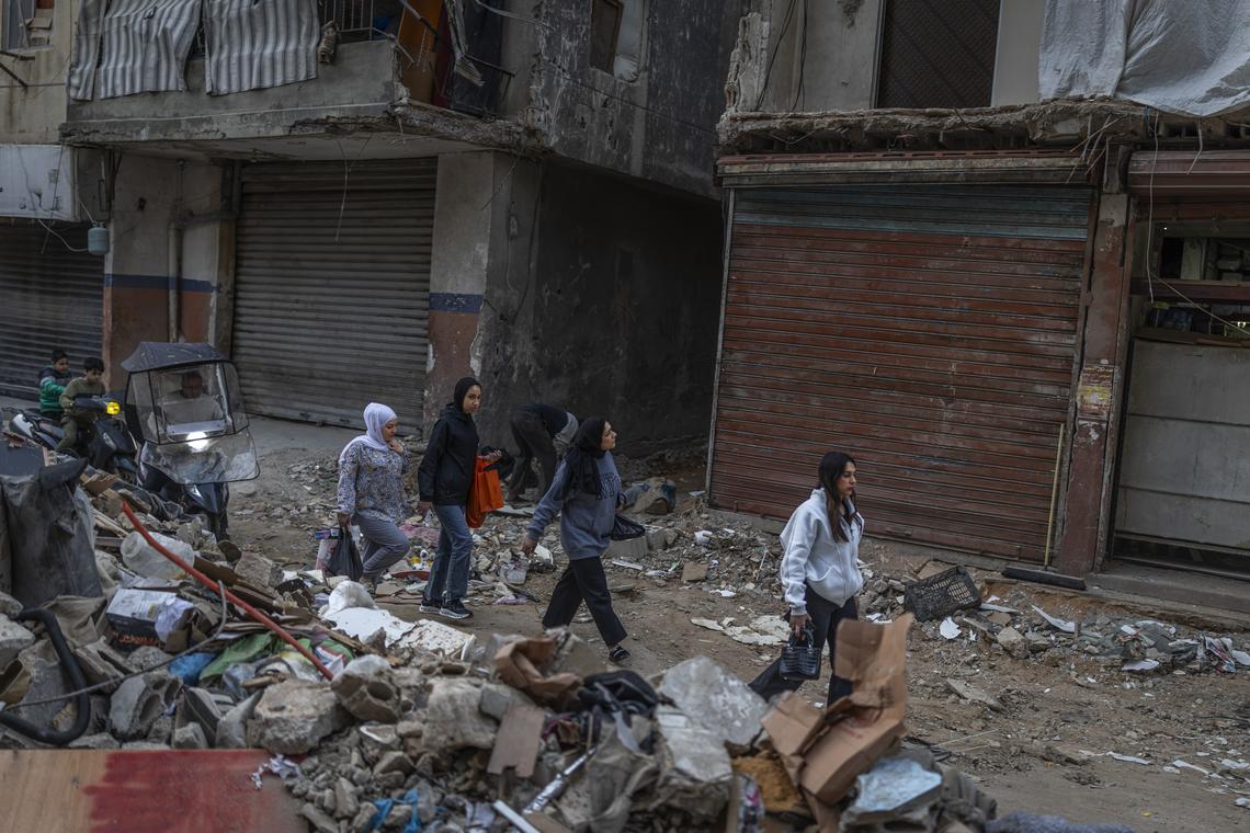 People walk near the debris of buildings destroyed by airstrikes in the Hay El Sellom neighborhood of Beirut, Lebanon, following the announcement of a ceasefire, on Sunday, April 19, 2026. (Diego Ibarra Sánchez/The New York Times)